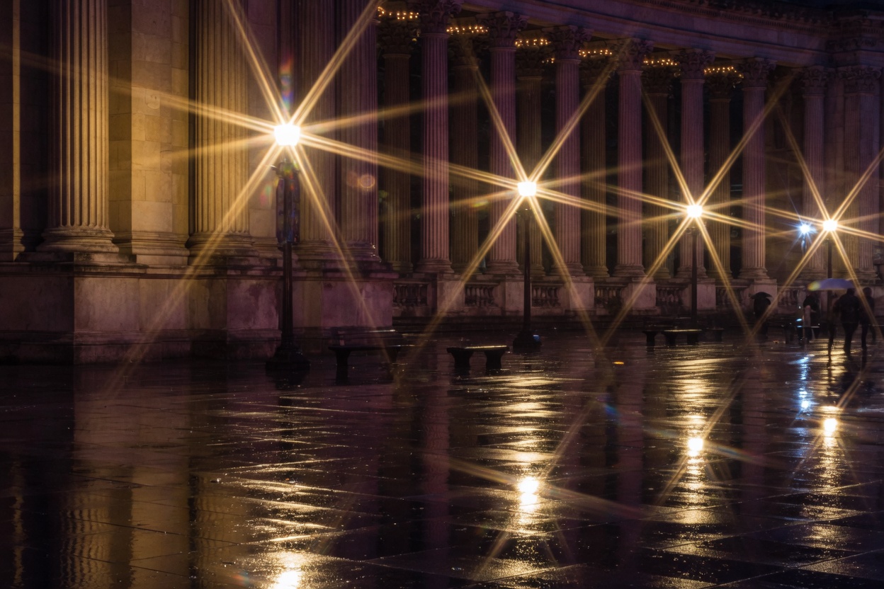 Night plaza with six-pointed sunstars on street lamps, the look of a stopped-down six-blade iris.